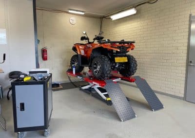 Oranssinpunainen mönkijä korjattavana Parikkalan Autotarvikkeen pienkonekorjaamossa